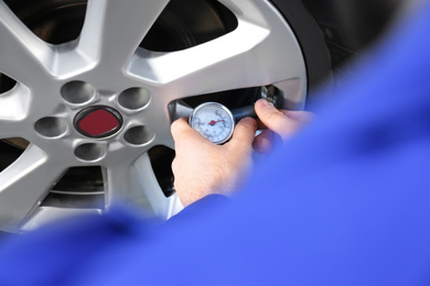 Photo of Mechanic checking tire air pressure at car service, closeup