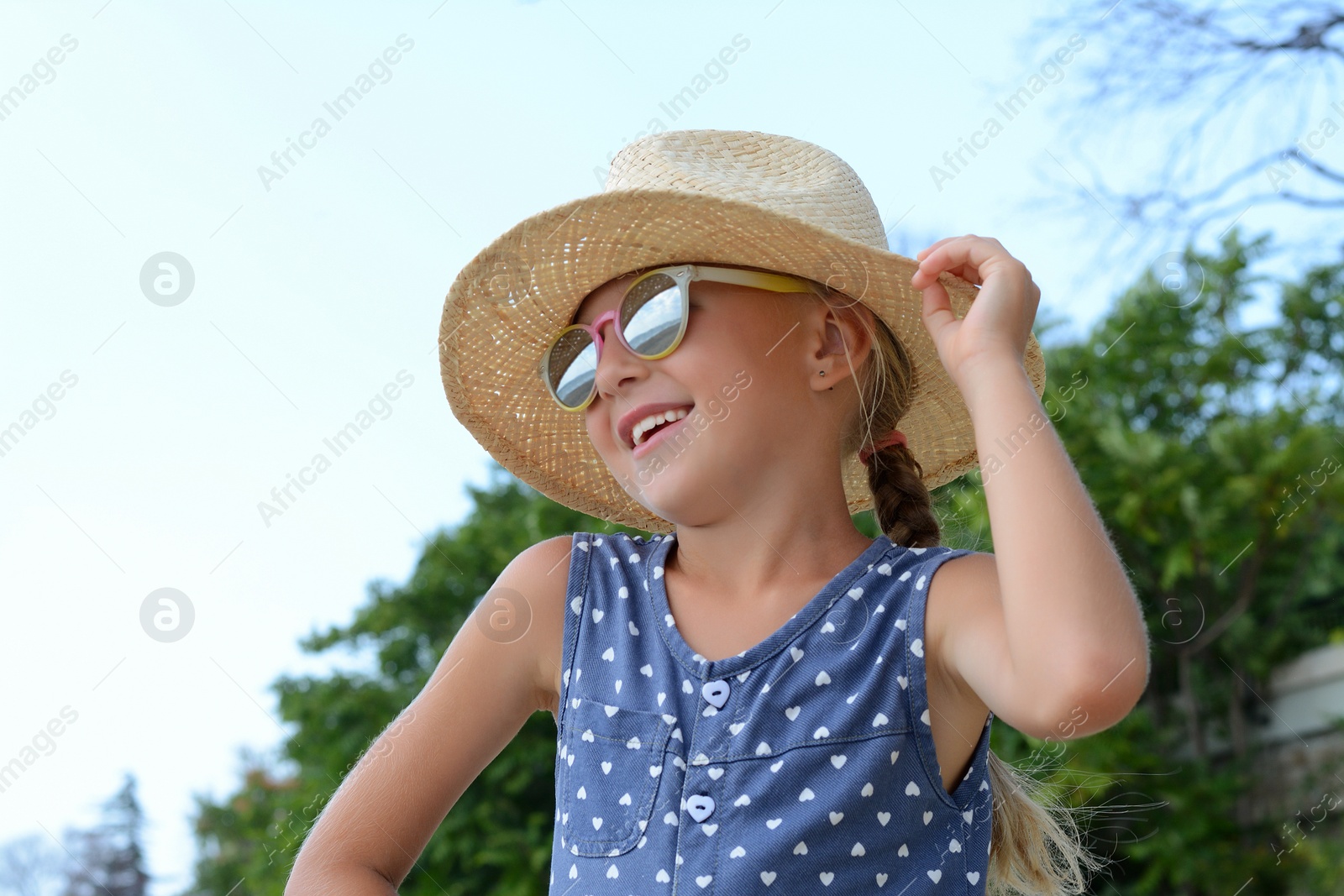 Photo of Little girl wearing sunglasses and hat at beach on sunny day