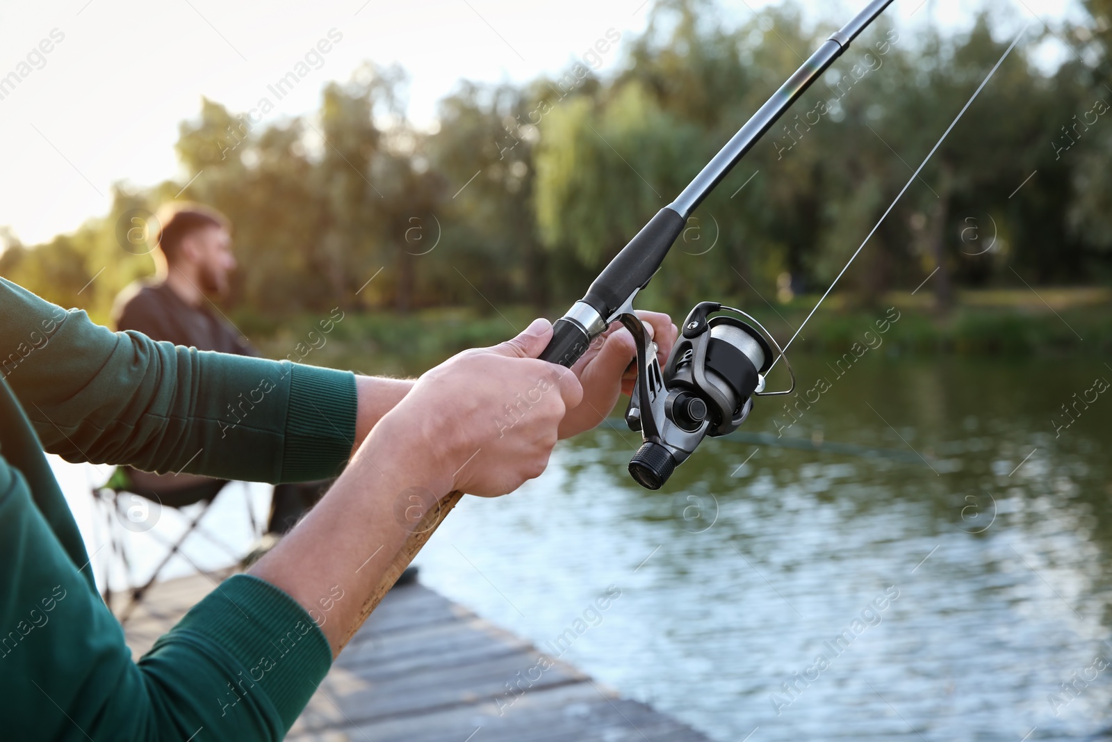 Photo of Man with rod fishing at riverside. Recreational activity