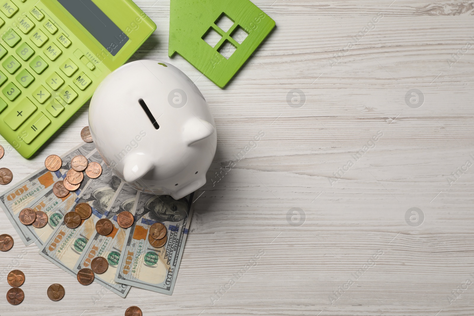 Photo of Piggy bank, house model, calculator and money on white wooden table, flat lay. Space for text