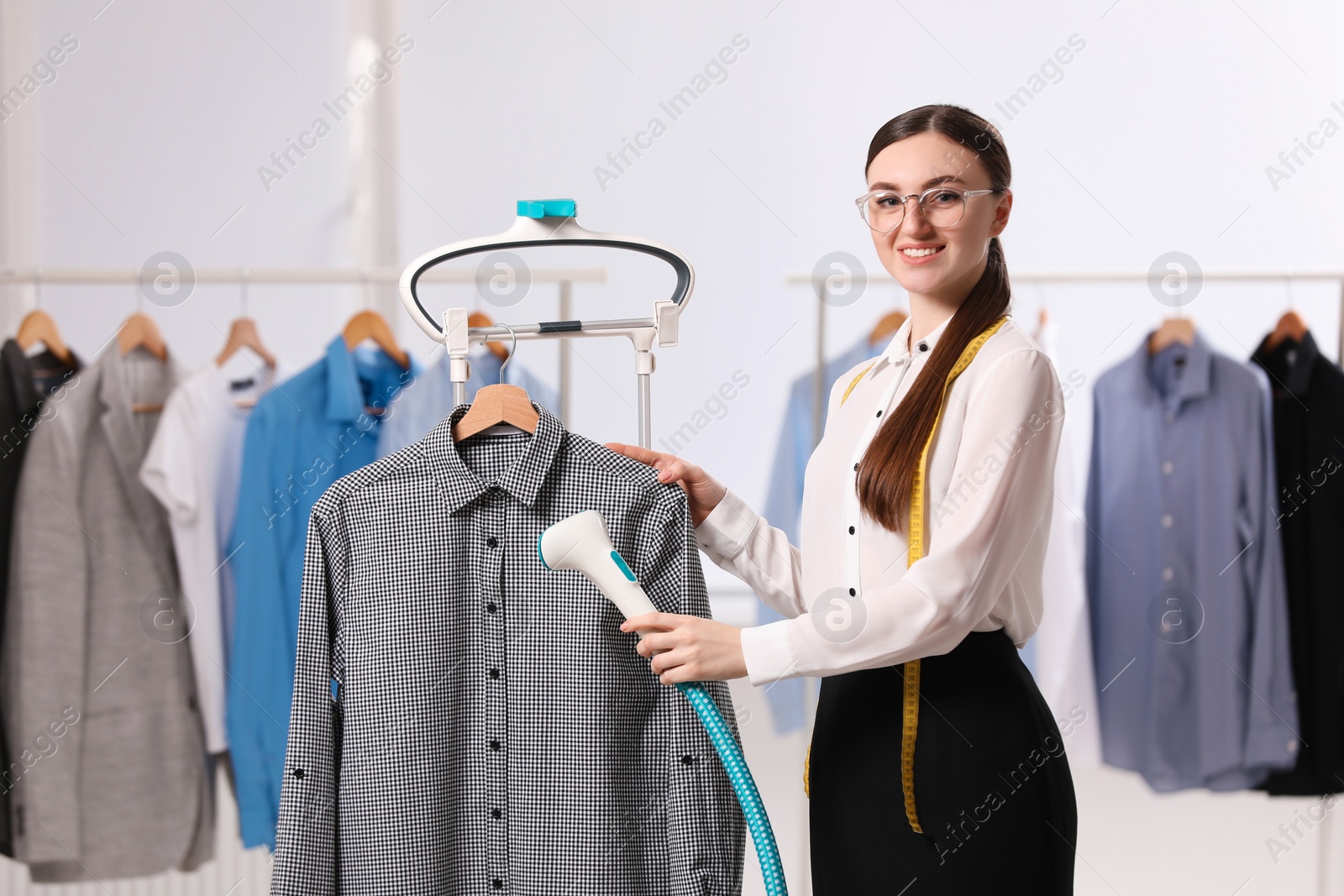 Photo of Woman steaming shirt on hanger in room