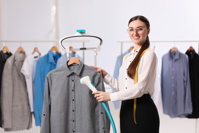 Woman steaming shirt on hanger in room