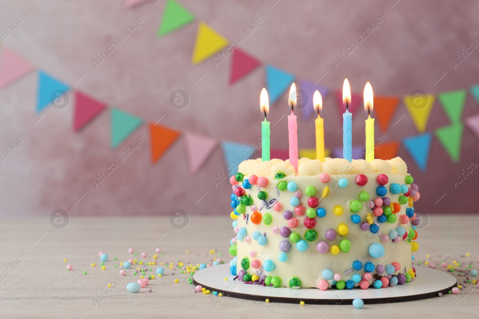 Photo of Cute bento cake with tasty cream and burning candles on white wooden table. Space for text