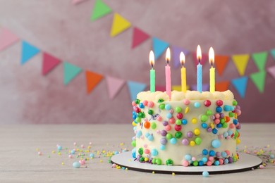 Photo of Cute bento cake with tasty cream and burning candles on white wooden table. Space for text