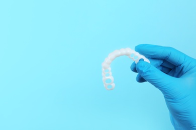 Photo of Dentist holding teeth cover on color background. Space for text