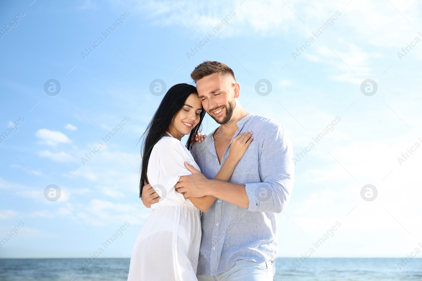 Photo of Happy young couple near sea on sunny day. Beach holiday