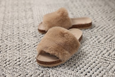 Photo of Brown soft slippers on crochet carpet, closeup