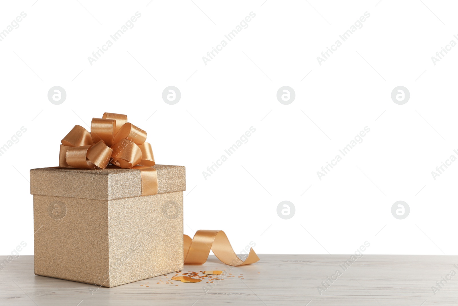 Photo of Golden gift box with ribbon and bow on grey table. Space for text