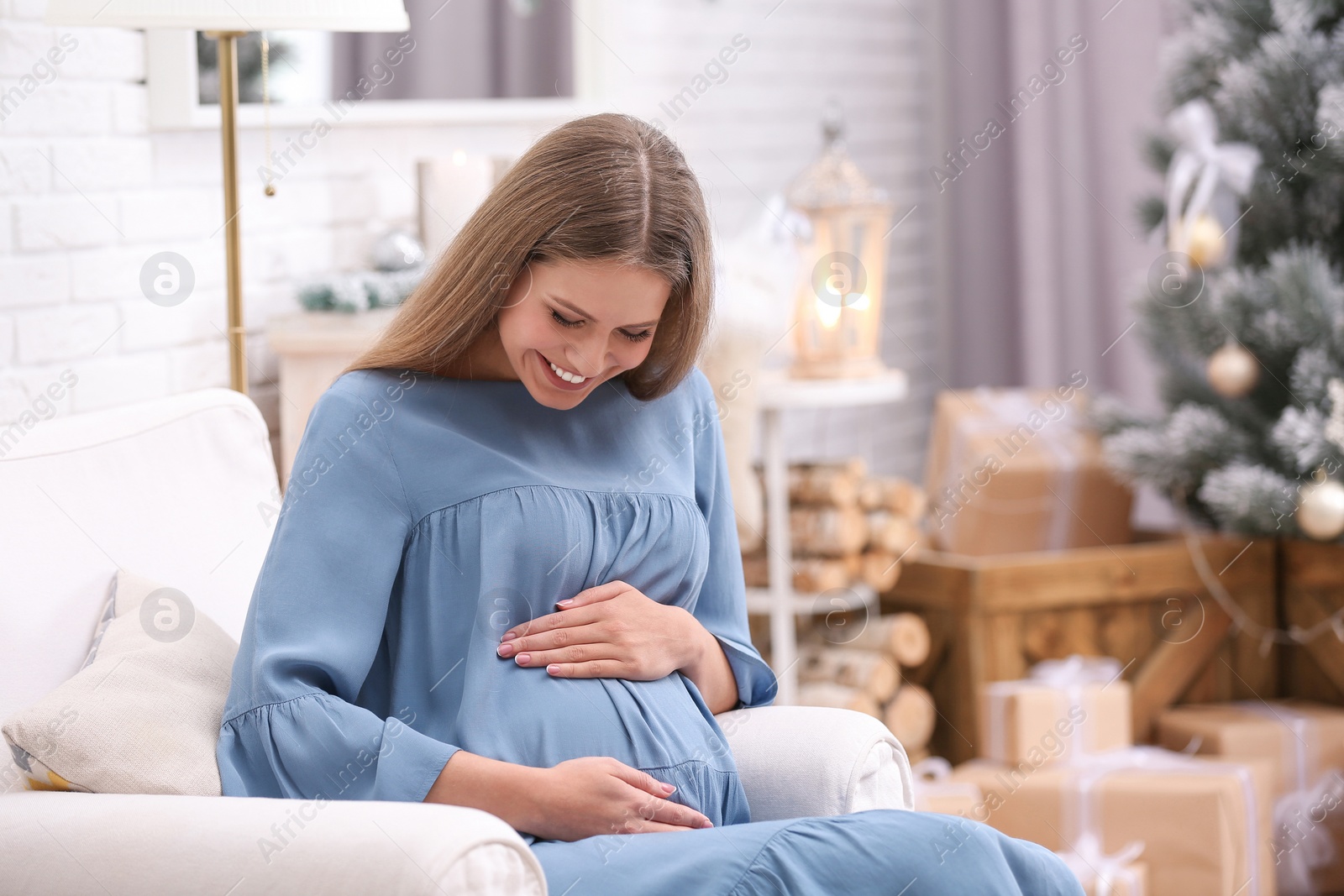 Photo of Young pregnant woman in room decorated for Christmas