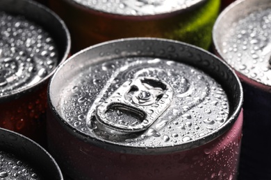 Aluminum cans of beverage covered with water drops as background, closeup