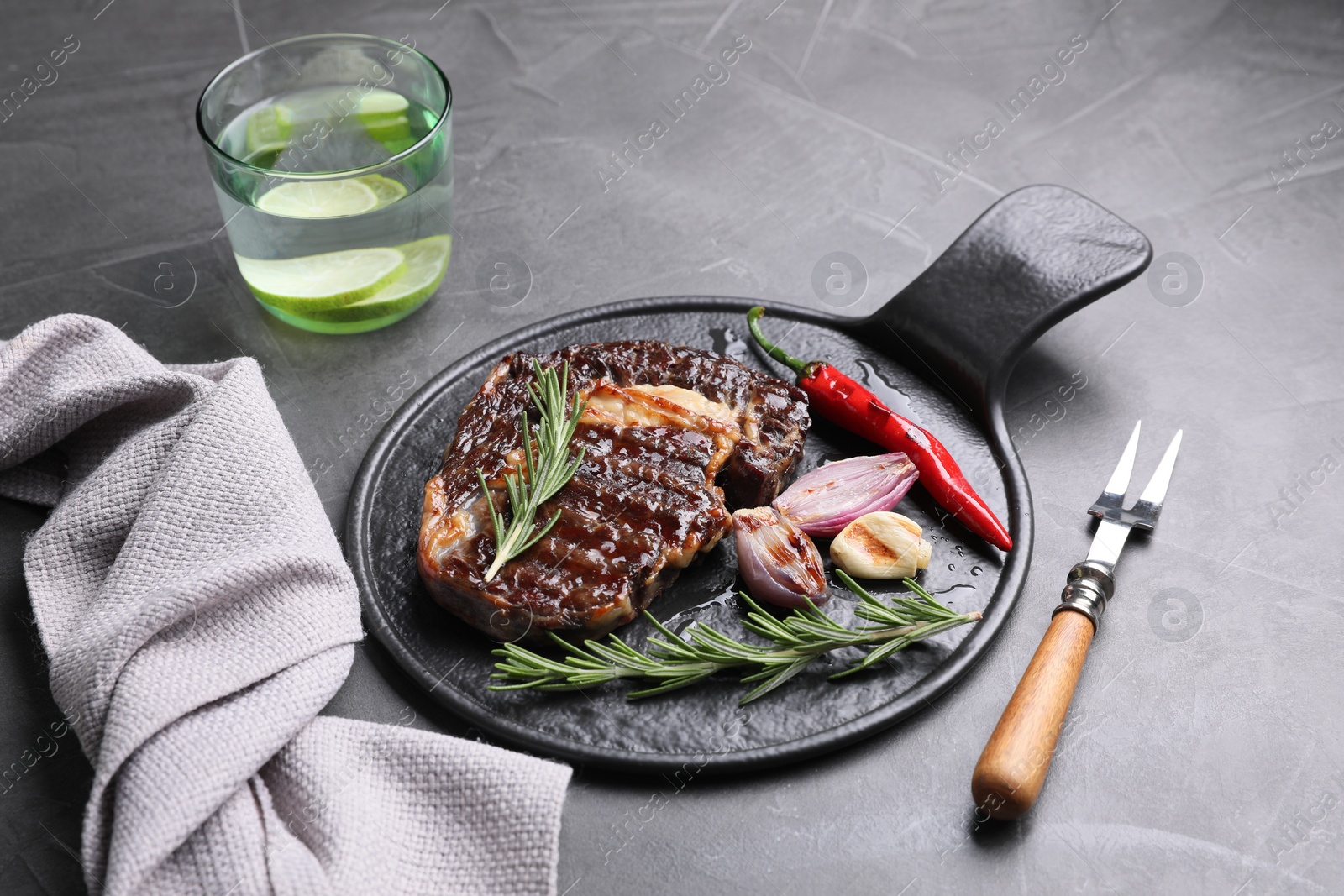 Photo of Delicious grilled beef meat served on gray textured table