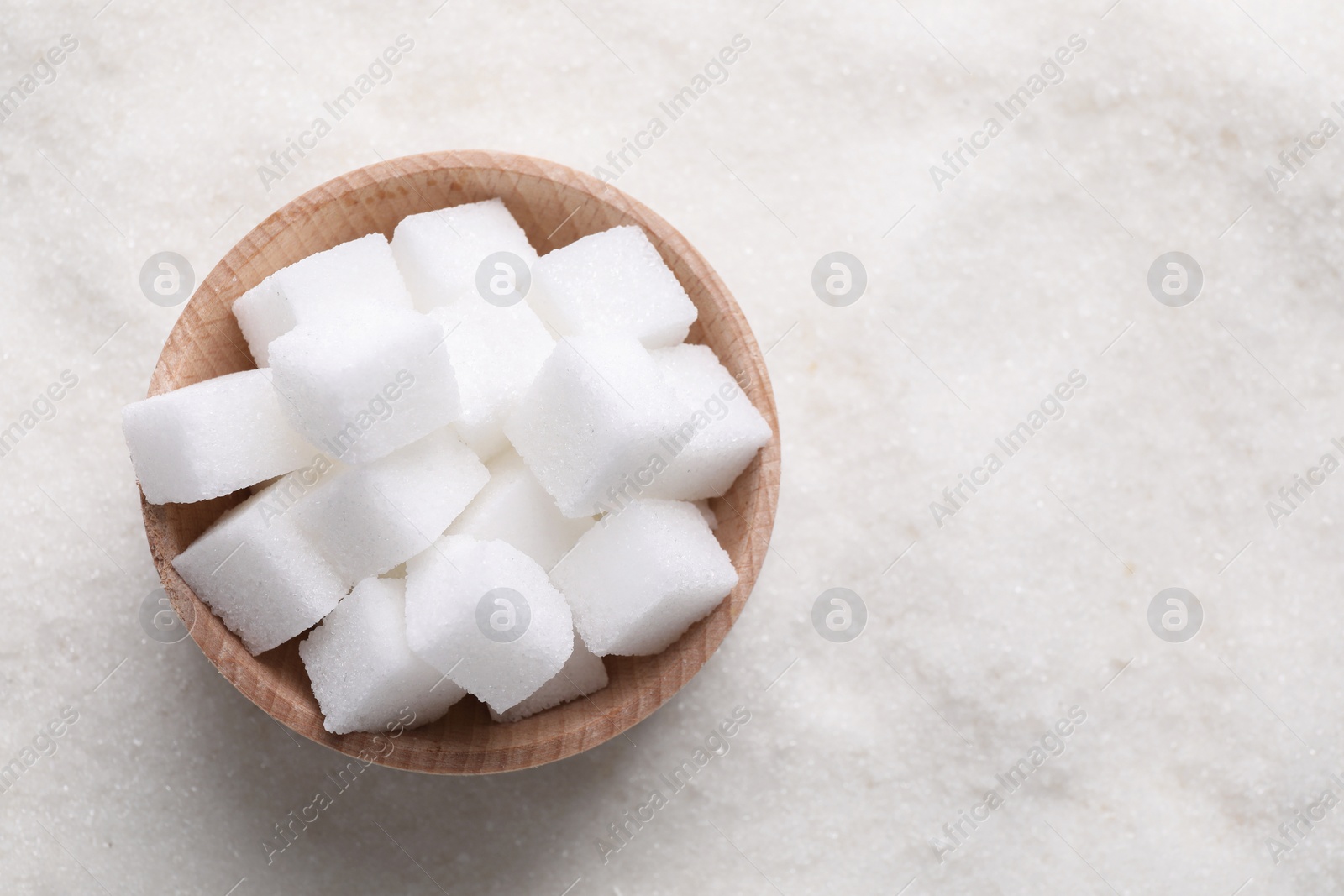 Photo of Different types of white sugar and bowl as background, top view. Space for text