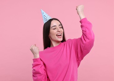 Happy woman in party hat on pink background