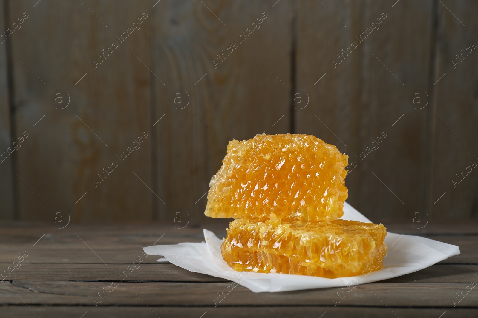 Photo of Natural honeycombs on wooden table, space for text