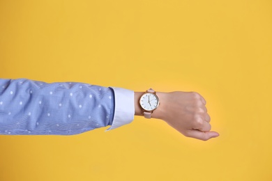 Young woman with wristwatch on color background. Time concept