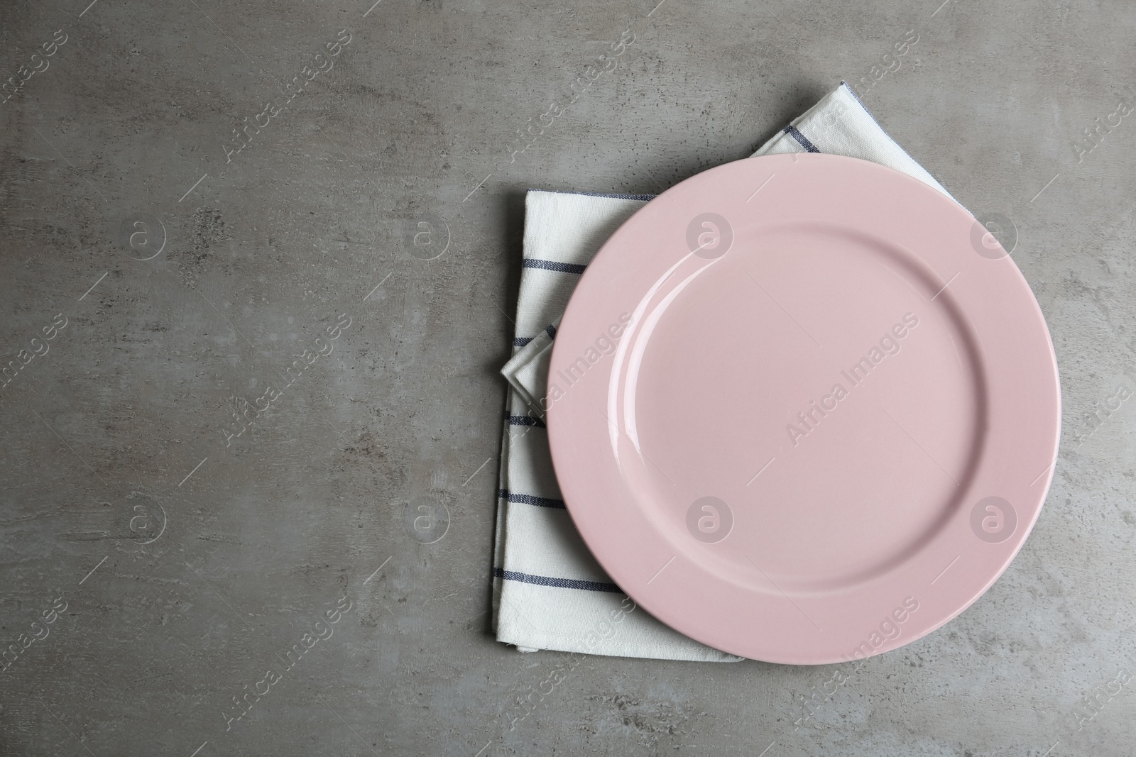 Photo of Empty plate and napkin on grey table, top view. Space for text