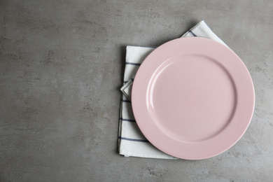 Photo of Empty plate and napkin on grey table, top view. Space for text