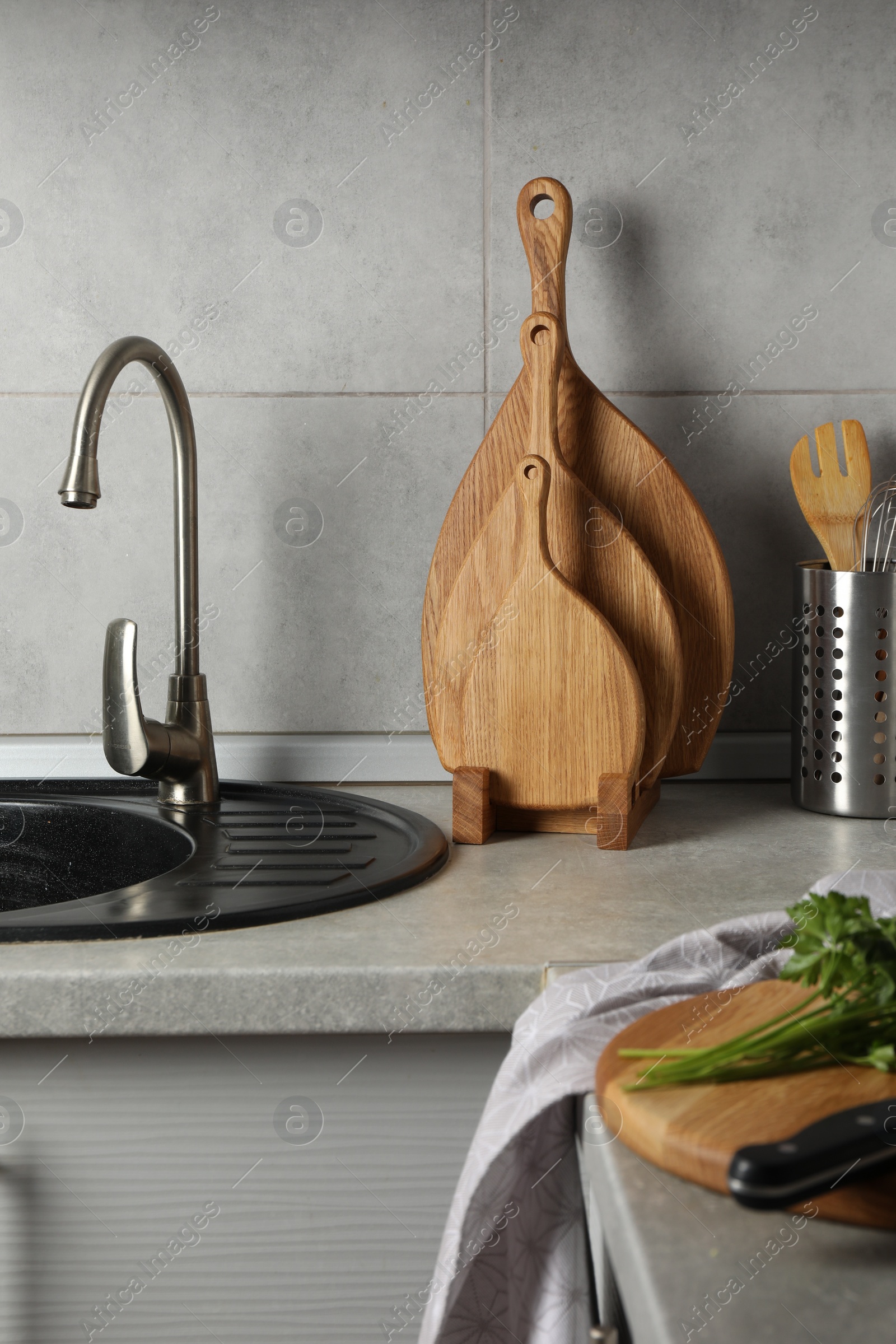 Photo of Wooden cutting boards and other cooking utensils on light grey countertop in kitchen