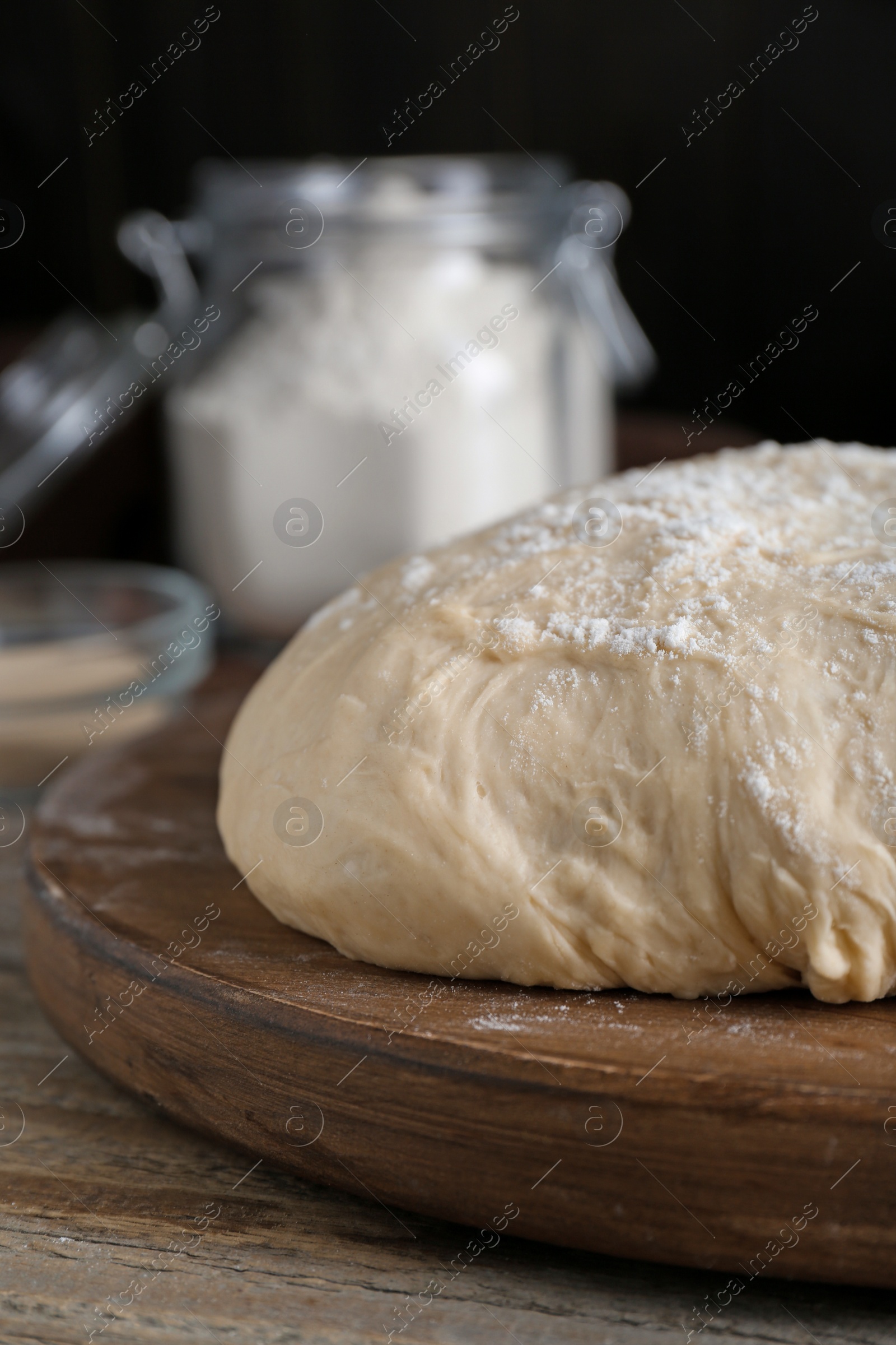 Photo of Fresh yeast dough with flour on wooden table, closeup