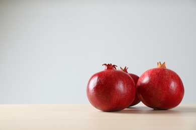 Ripe pomegranates on table against light background, space for text