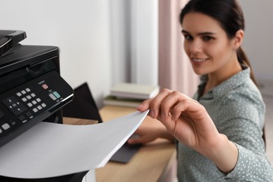 Photo of Woman using modern printer at workplace indoors, selective focus