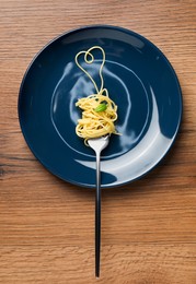 Heart made with spaghetti and fork on wooden table, top view