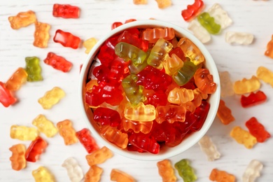 Bowl with delicious jelly bears on light table, top view