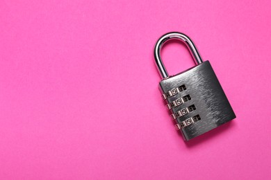 Photo of One steel combination padlock on pink background, top view. Space for text