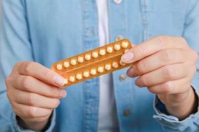 Woman holding blister with birth control pills, closeup