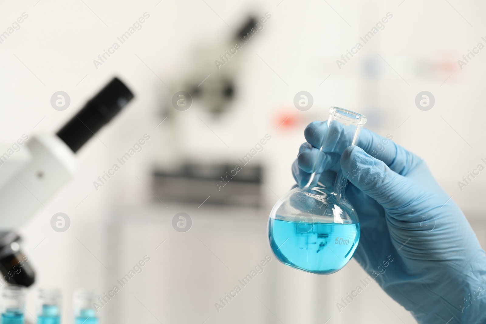 Photo of Scientist holding flask in laboratory, closeup view. Space for text