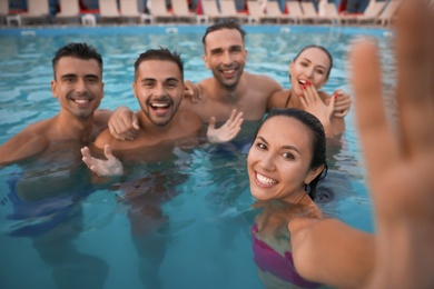 Photo of Happy young friends taking selfie in swimming pool