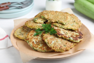 Photo of Delicious zucchini fritters served on white wooden table, closeup