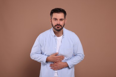 Man suffering from stomach pain on light brown background