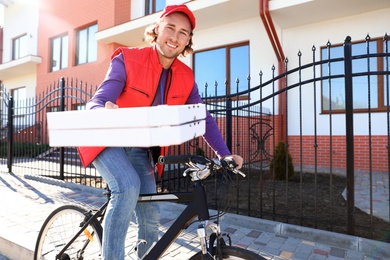 Photo of Male courier on bicycle delivering food in city