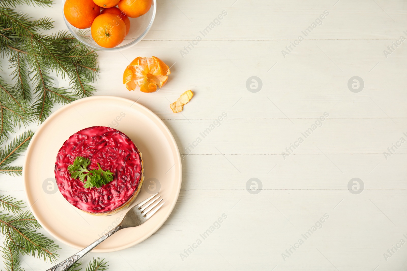 Photo of Flat lay composition with herring under fur coat, tangerines and fir branches on white wooden table, space for text. Traditional russian salad