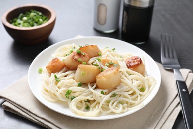 Delicious scallop pasta with green onion served on grey table