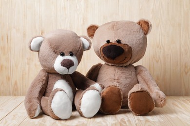 Photo of Cute teddy bears on table near wooden wall