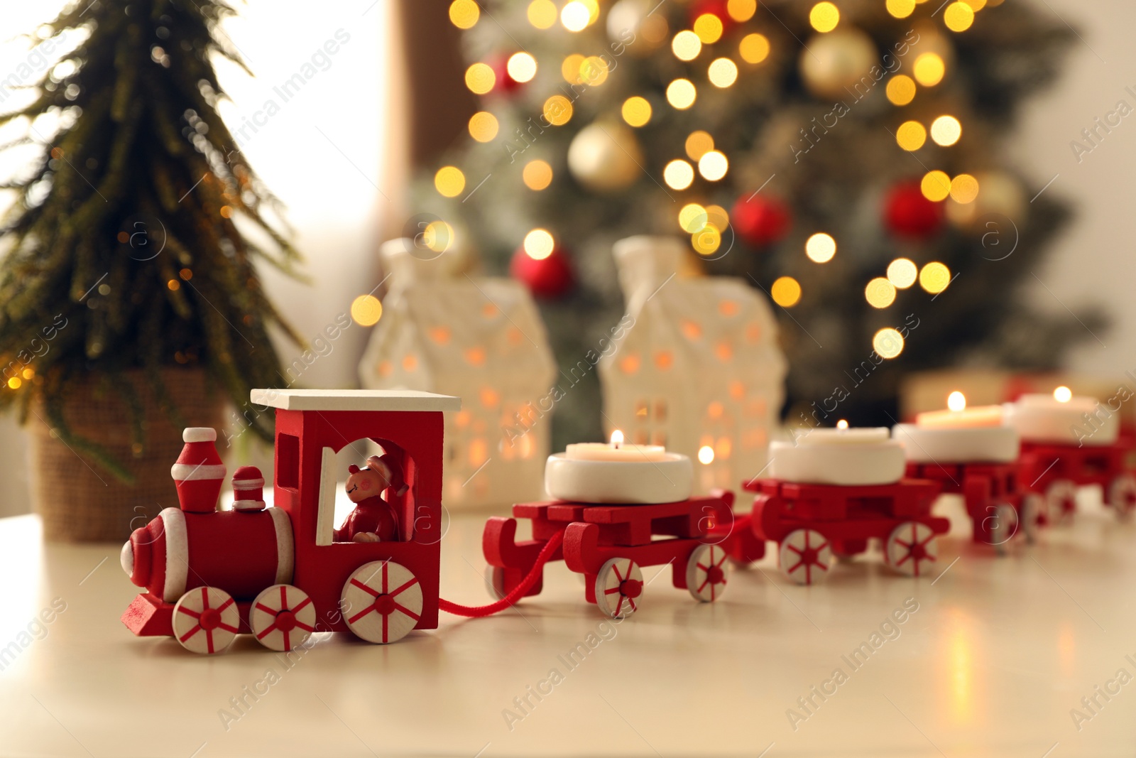 Photo of Red toy train as Christmas candle holder on white table in room