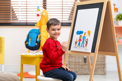 Little child painting on easel in room