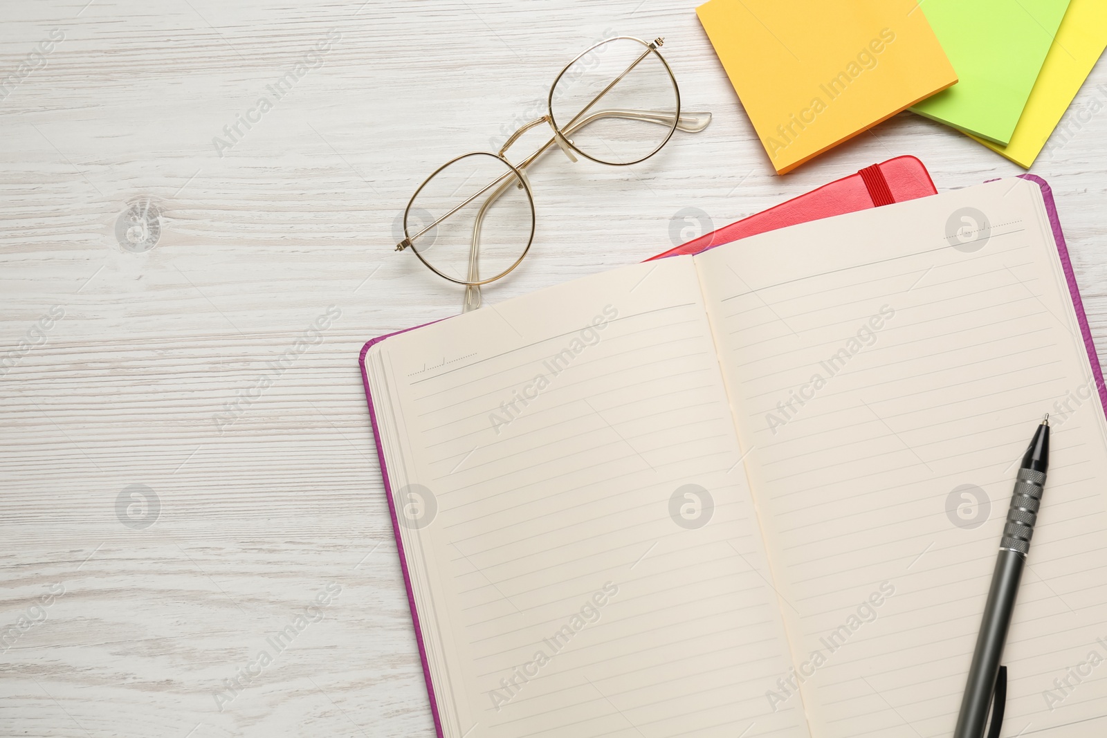 Photo of Notebooks, pen, glasses and sticky notes on white wooden table, flat lay. Space for text