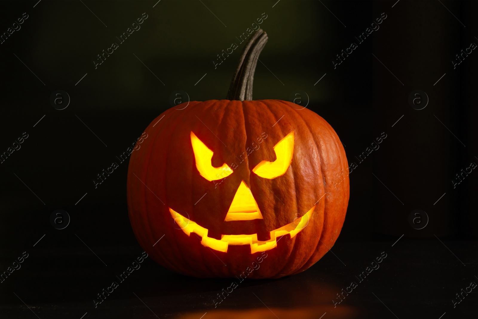 Photo of Scary jack o'lantern pumpkin in darkness. Halloween decor