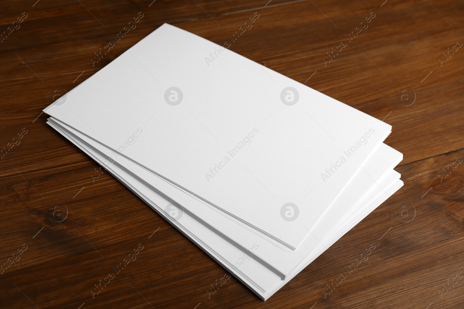 Photo of Stack of blank paper sheets on wooden table. Brochure design