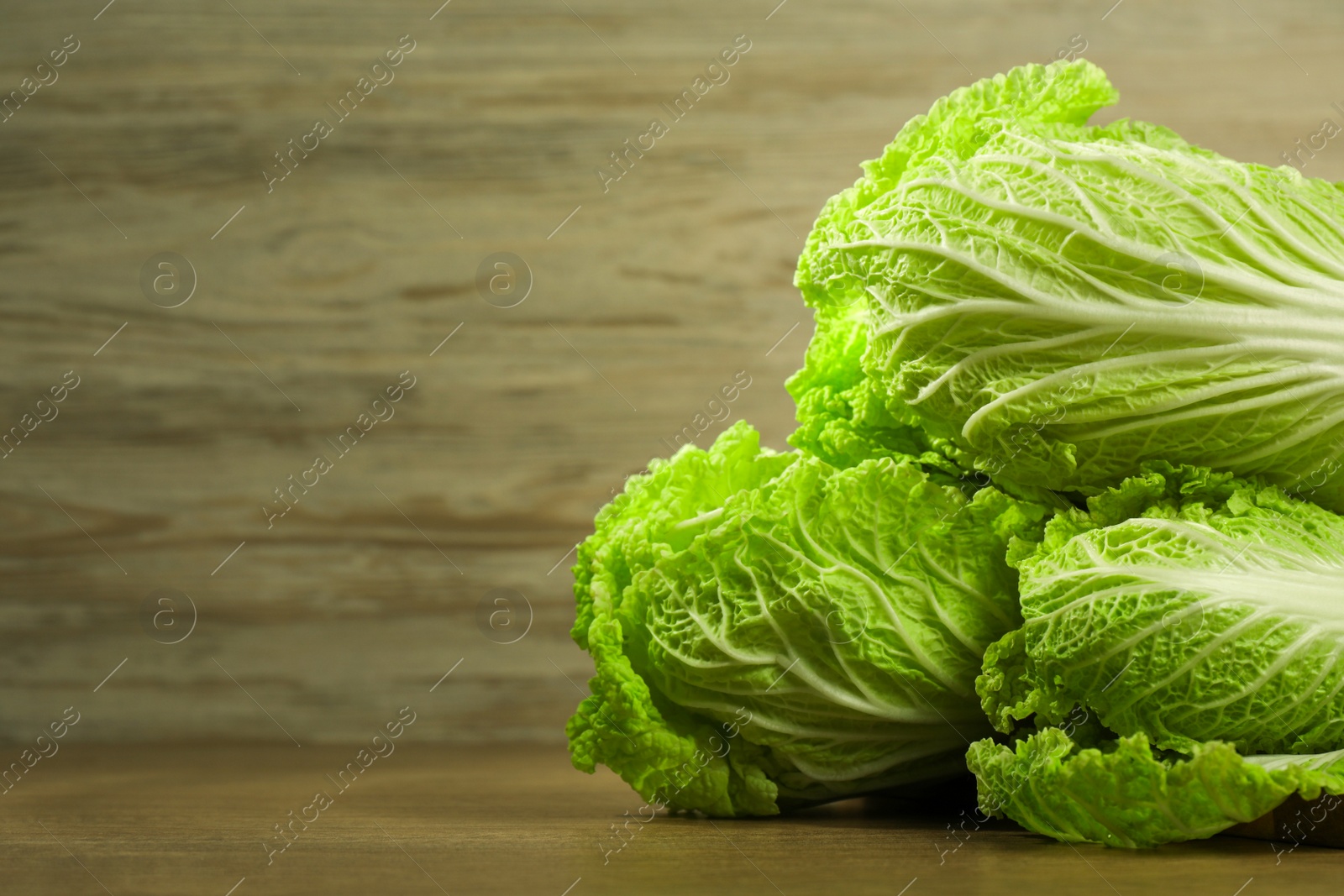 Photo of Fresh ripe Chinese cabbages on wooden table, closeup view. Space for text