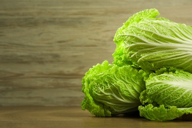 Fresh ripe Chinese cabbages on wooden table, closeup view. Space for text