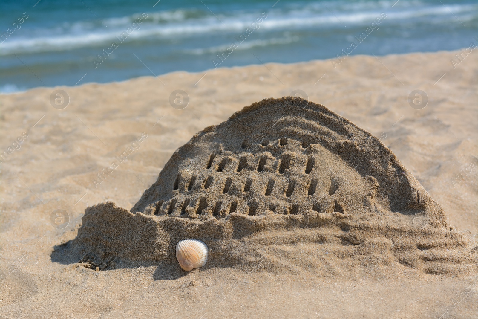 Photo of Beach with sand castle near sea on sunny day