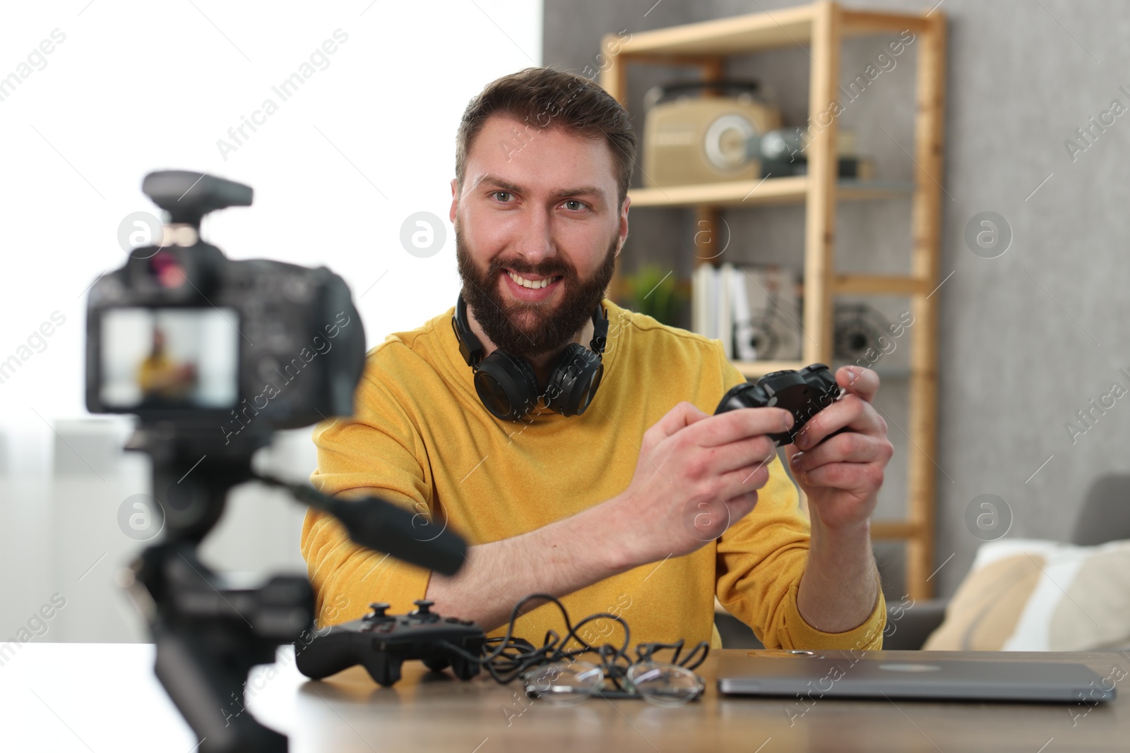 Photo of Smiling technology blogger recording video review about game controllers at home