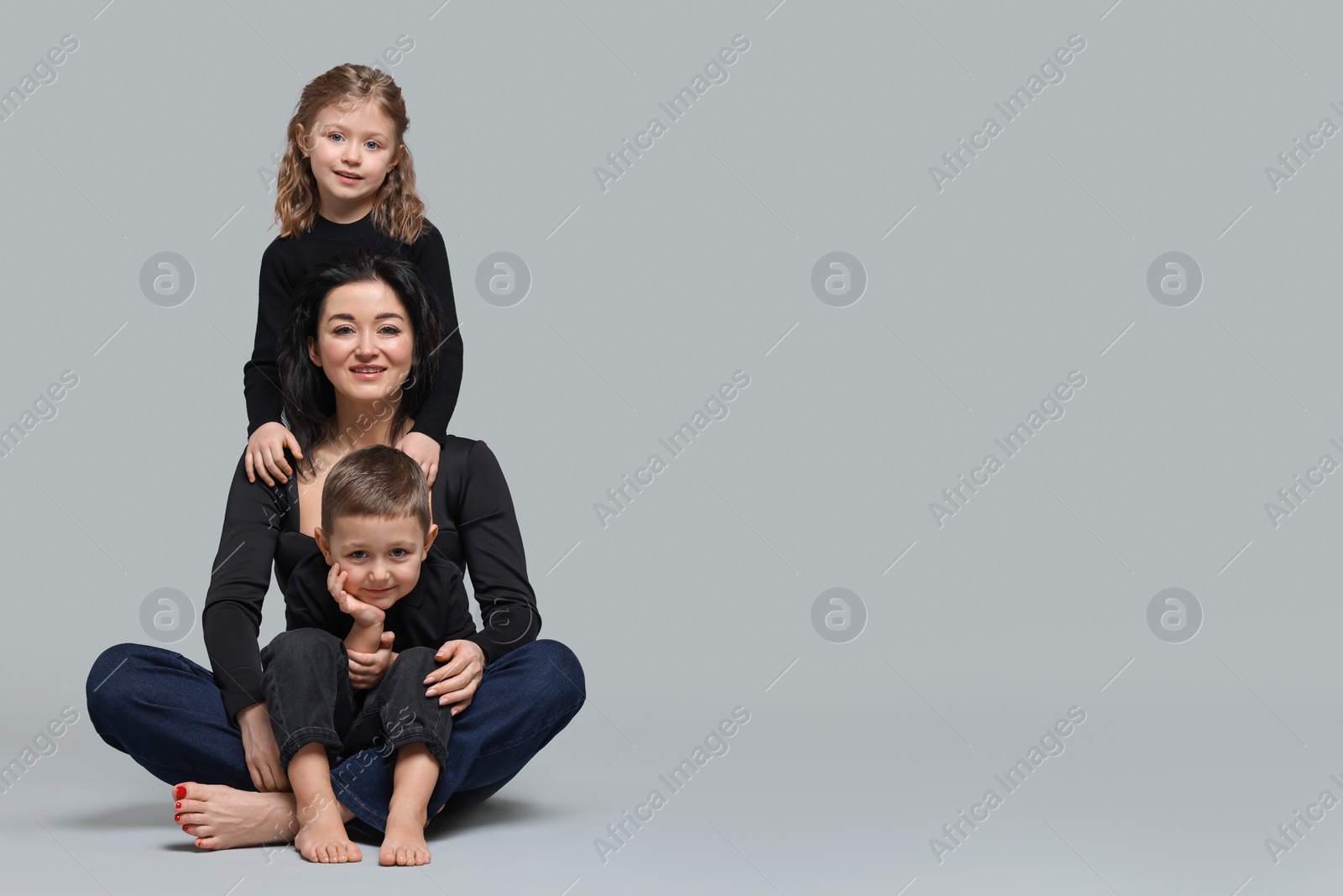 Photo of Little children with their mother on grey background. Space for text