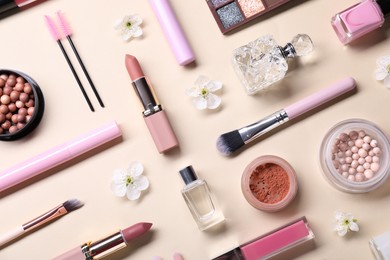 Flat lay composition with different makeup products and beautiful spring flowers on beige background