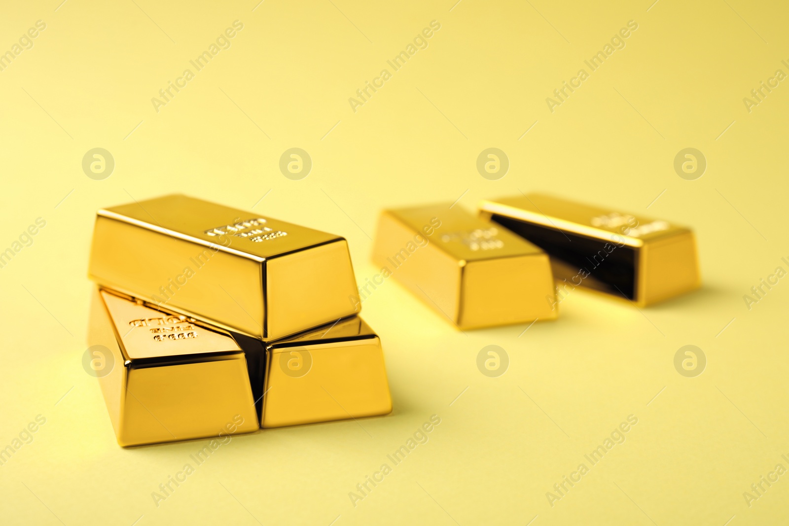 Photo of Shiny gold bars on yellow background. Space for text