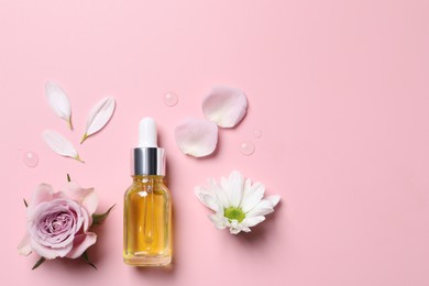 Photo of Bottle of cosmetic serum and beautiful flowers on pink background, flat lay. Space for text